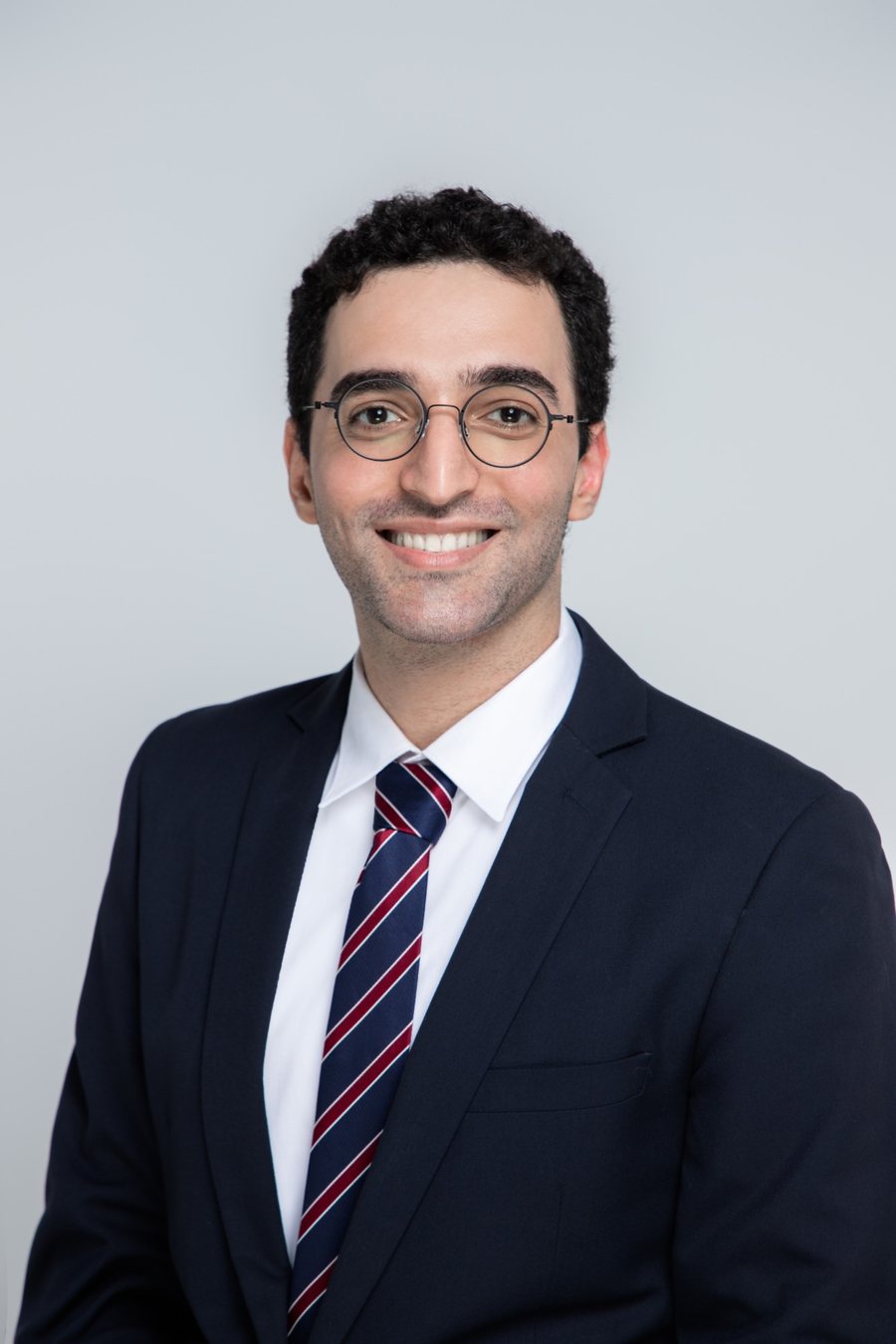 Portrait of Benjamin Motahari in a navy suit and round glasses